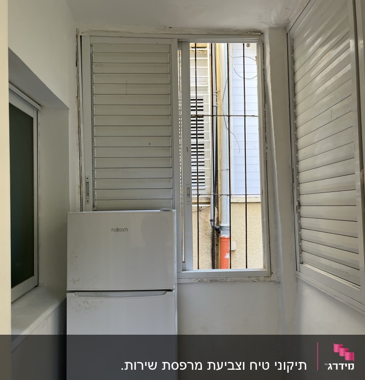 מקרר לבן ליד חלון עם תריסים